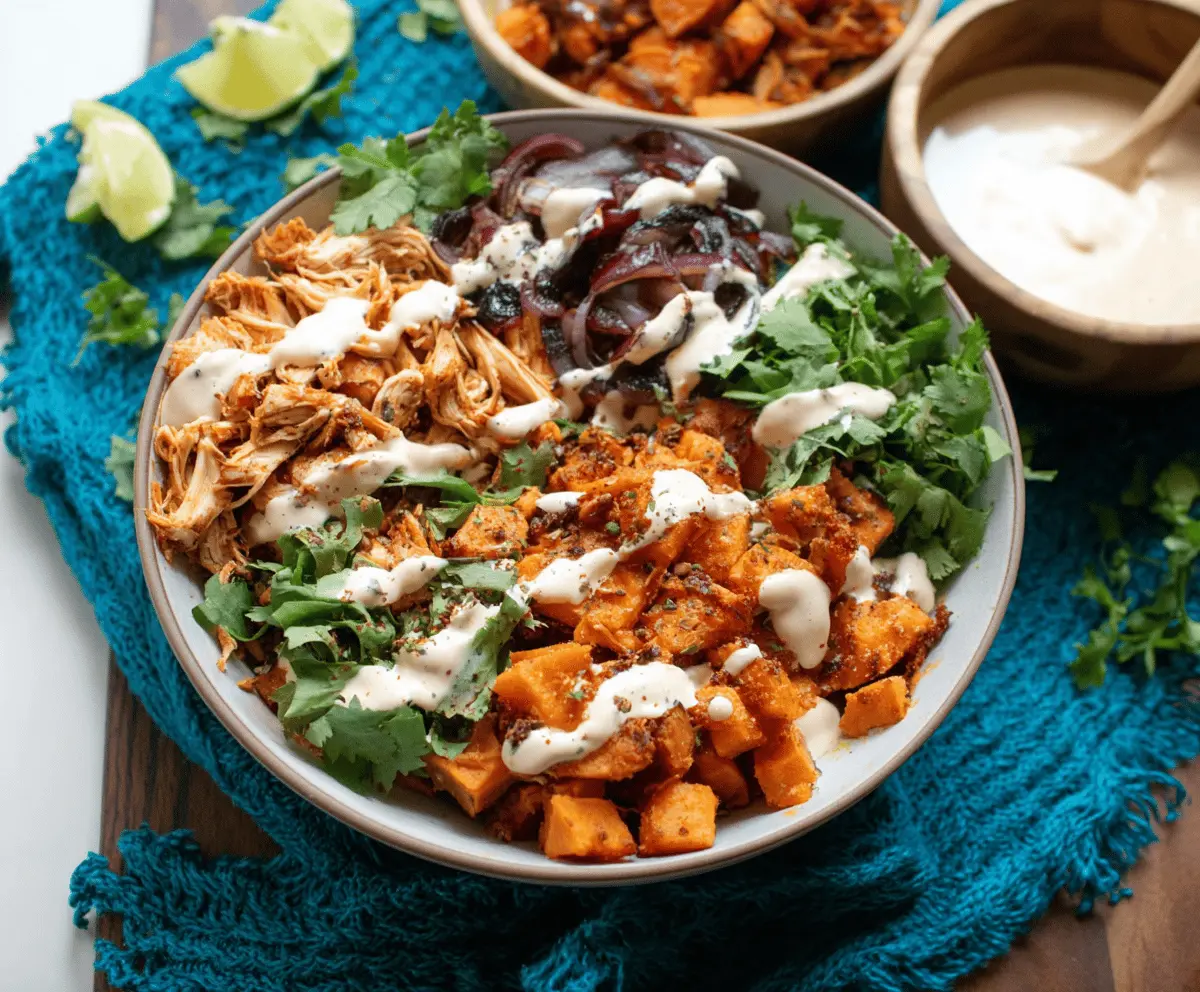 Delicious pulled chicken sweet potato bowls topped with fresh herbs and colorful vegetables, served in a white bowl for a healthy, flavorful meal.