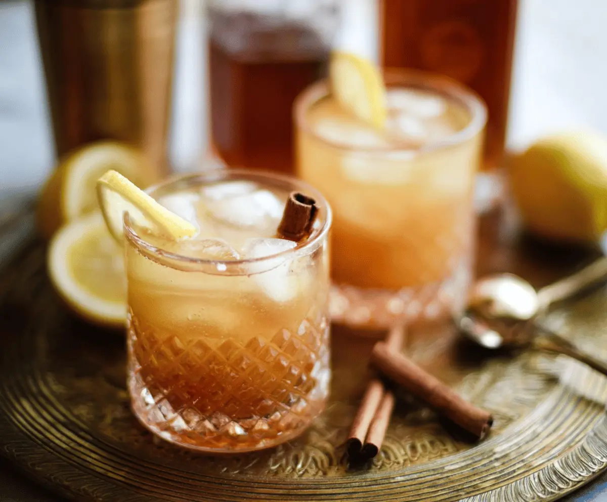 Refreshing Cinnamon Maple Whiskey Sour cocktail garnished with cinnamon stick and citrus slice.