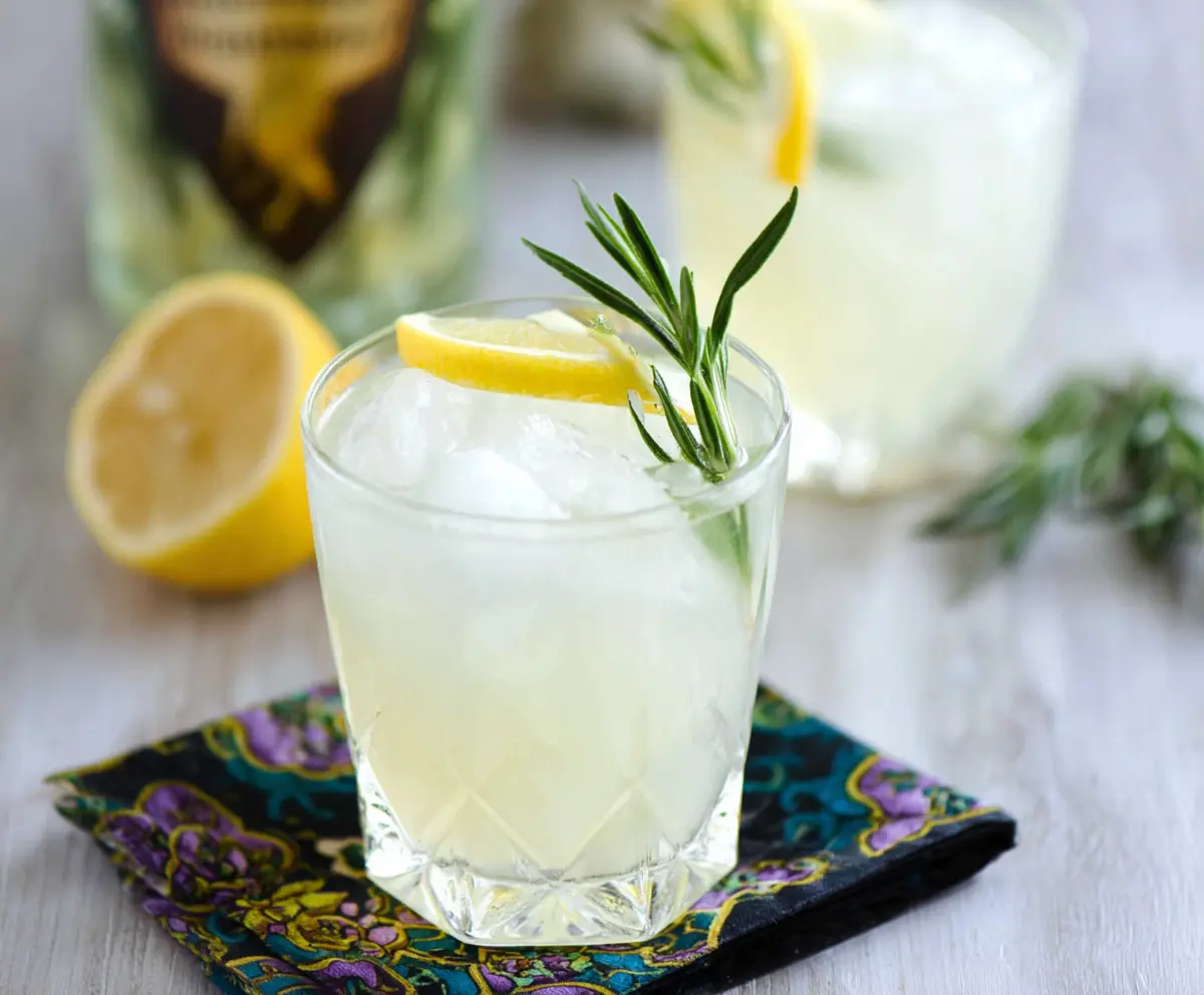 Refreshing Rosemary Gin Fizz cocktail garnished with fresh rosemary and lemon slice.