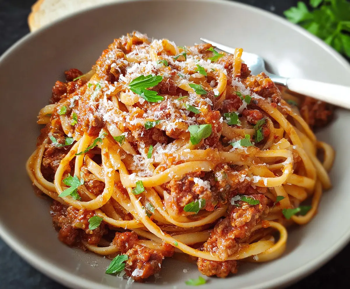 Delicious homemade Bolognese pasta topped with fresh herbs and grated cheese.