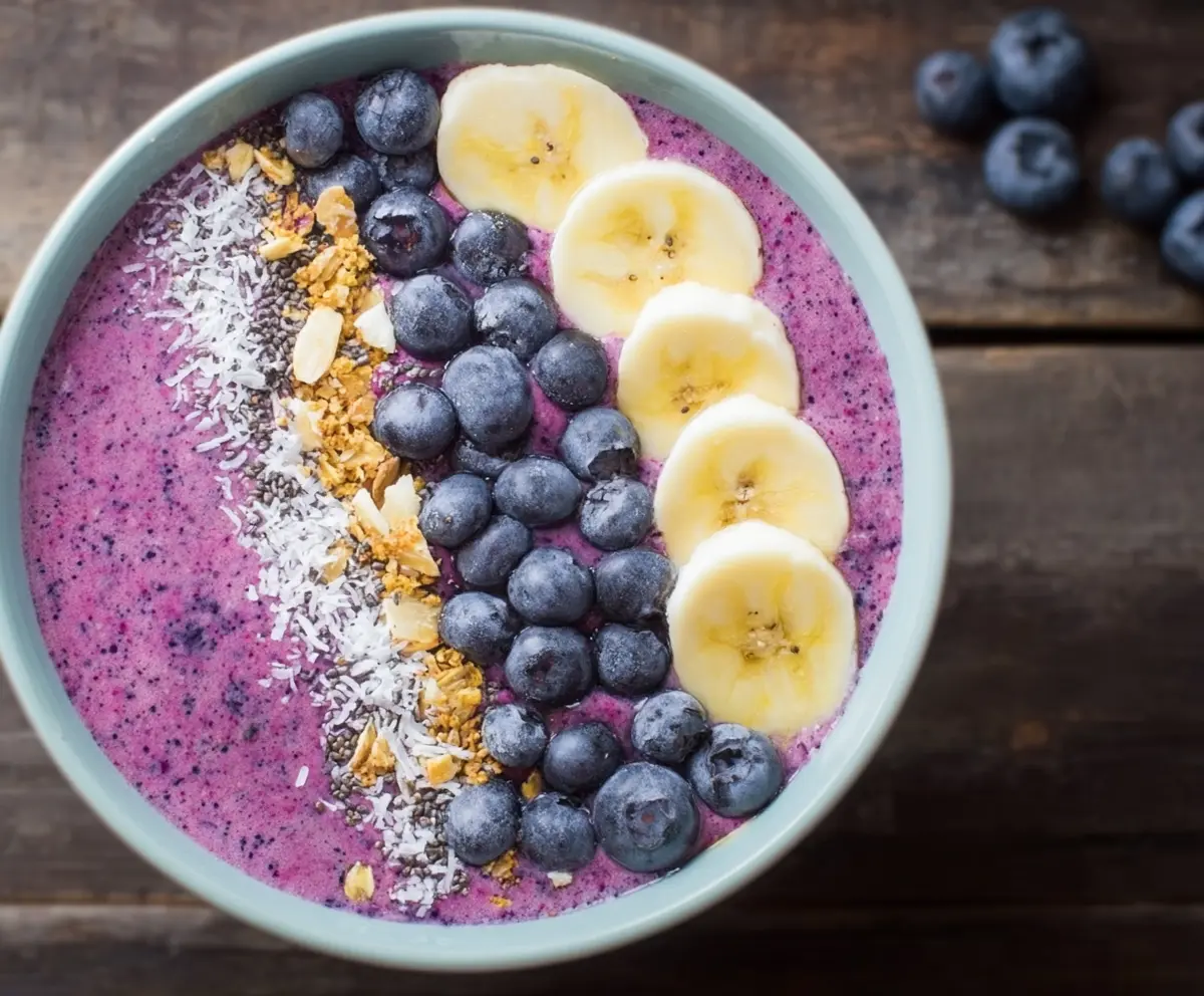 Healthy blueberry smoothie bowl topped with fresh berries and granola, perfect for breakfast or a snack.
