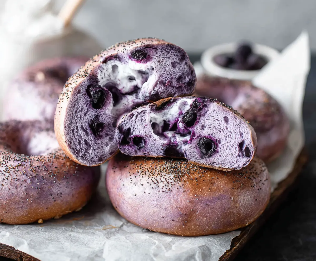 Fresh blueberry bagels on a breakfast plate with blueberries and cream cheese.