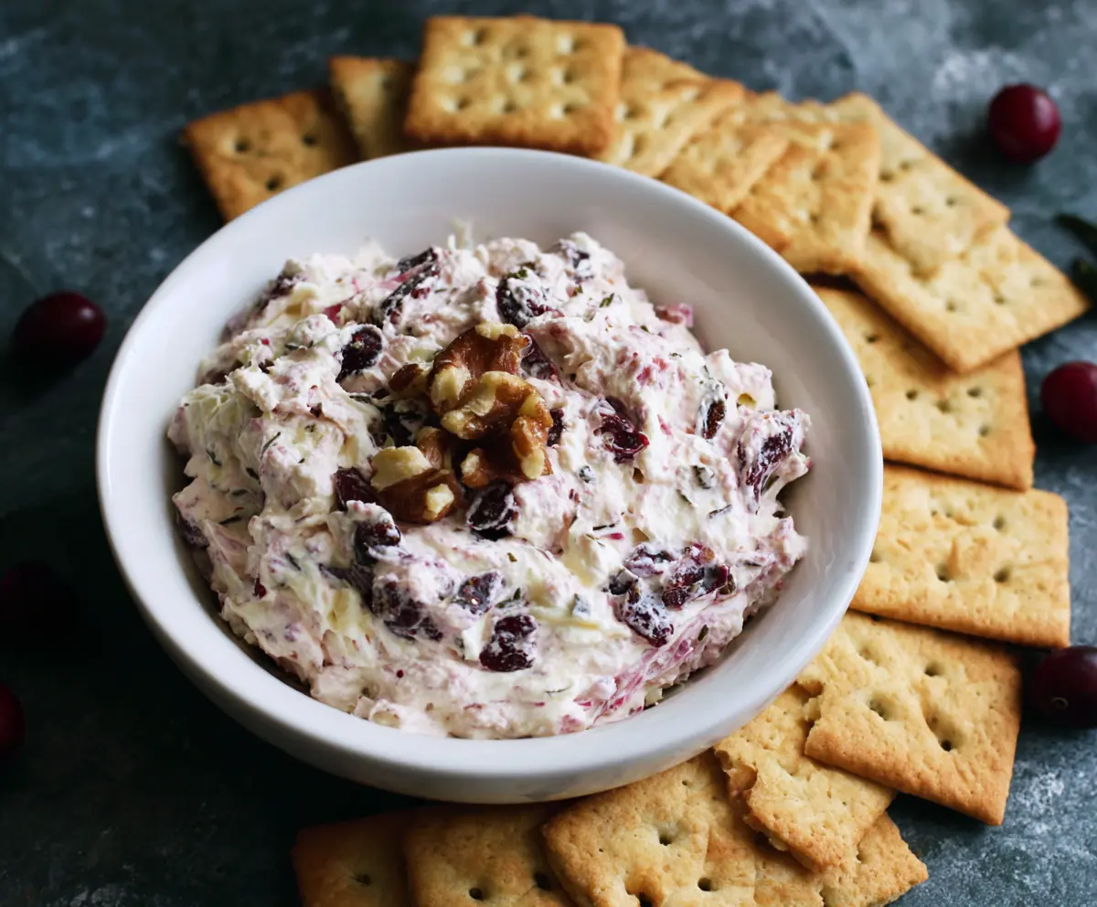 Creamy cranberry walnut dip topped with fresh cranberries and chopped walnuts, ideal for holiday appetizers.