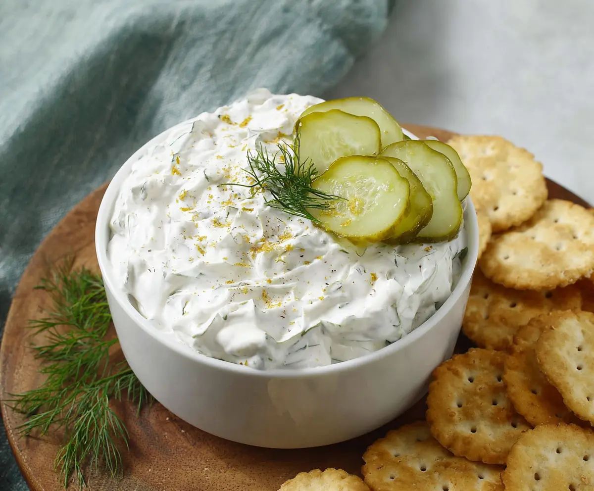 Creamy dill pickle dip served with fresh vegetables and chips for a flavorful snack.