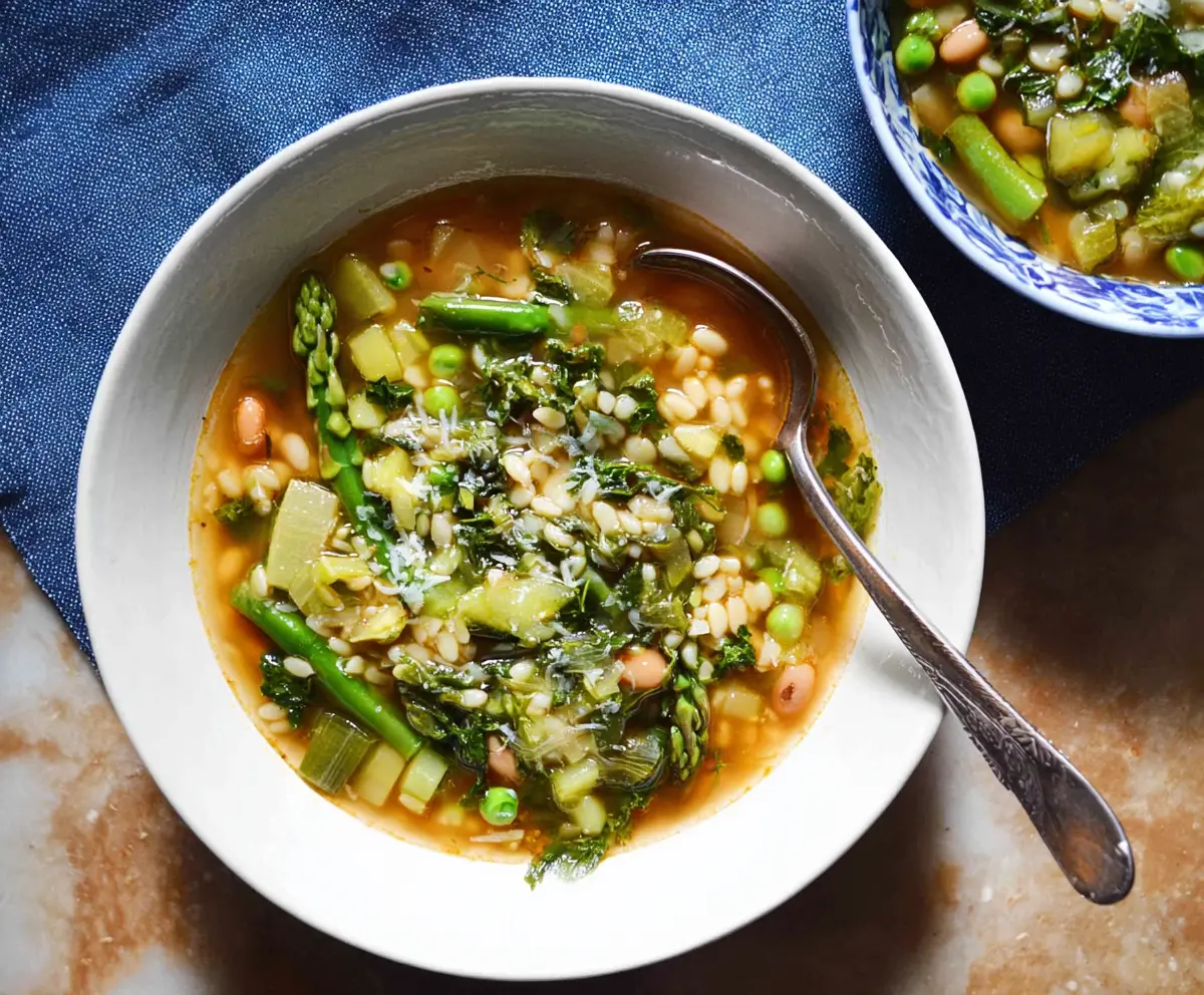 A bowl of fresh Spring Minestrone Soup with colorful vegetables and herbs garnished with basil.