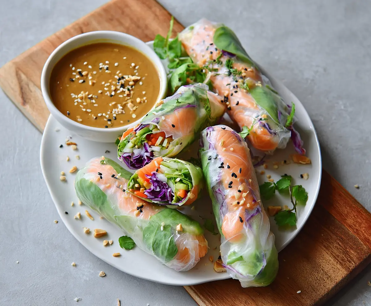 Fresh salmon spring rolls with vibrant vegetables served with creamy peanut sauce
